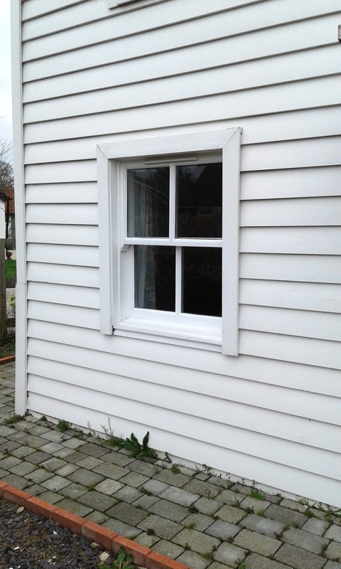 Bespoke white small sash window in weathboarded exterior
